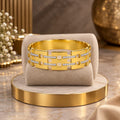 Premium gold-finish stone-detail Kada displayed on a beige jewellery cushion
